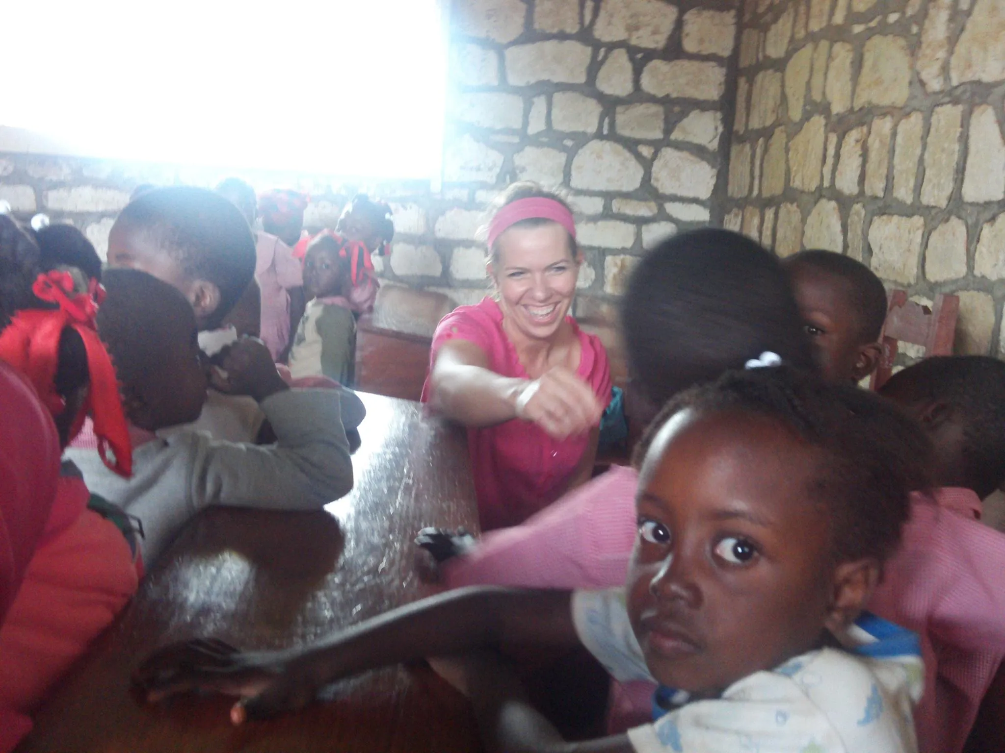 Jayme Sinclair sitting and working alongside a group of children at a partner program
